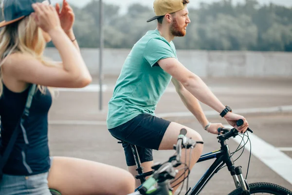 Vista lateral de una pareja joven en bicicleta en el campo — Foto de Stock