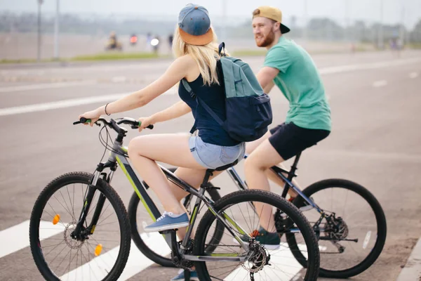 Sidovy av ett ungt par på cykel rida på landsbygden — Stockfoto