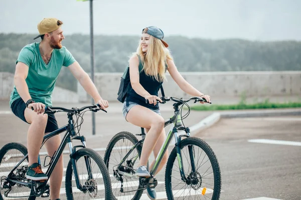 Casal atraente em um passeio de bicicleta em um dia ensolarado na cidade — Fotografia de Stock