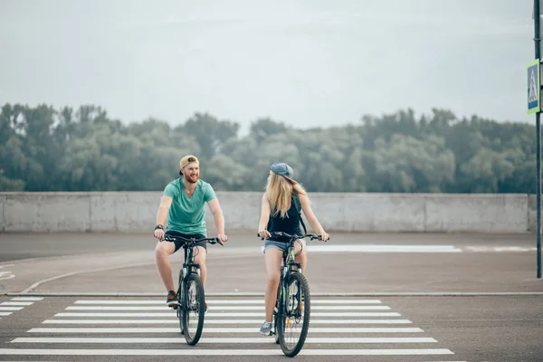 Atractiva pareja en un paseo en bicicleta en un día soleado en la ciudad — Foto de Stock