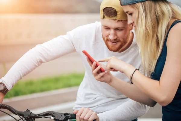 骑自行车到智能手机，看起来年轻开朗夫妇下载照片 — 图库照片