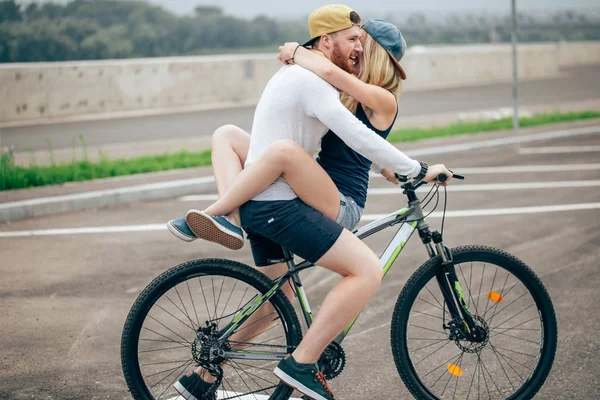 Szczęśliwy człowiek, dając dziewczyna windą na jego urządzenie miksujące rowerów na plaży — Zdjęcie stockowe