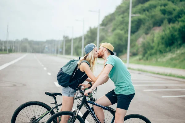 Romantisches Sportpaar küsst sich vor verschwommenem Hintergrund mit Fahrrädern — Stockfoto
