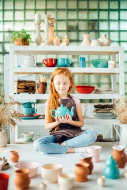 Kızıl saçlı kız lotus poz Studio oturan seramik bardak yapılır