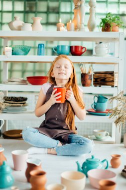 Kızıl saçlı kız lotus poz Studio oturan seramik bardak yapılır