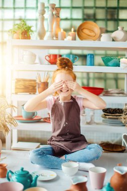 birçok fincanla kil atölye stüdyoda oturan Kızıl saçlı kız