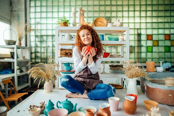 Рыжая женщина сидит в позе лотоса в глиняном магазине — стоковое фото