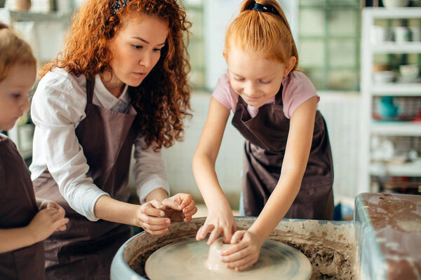 mother and two redhead daughters made clay cup with pottery wheel