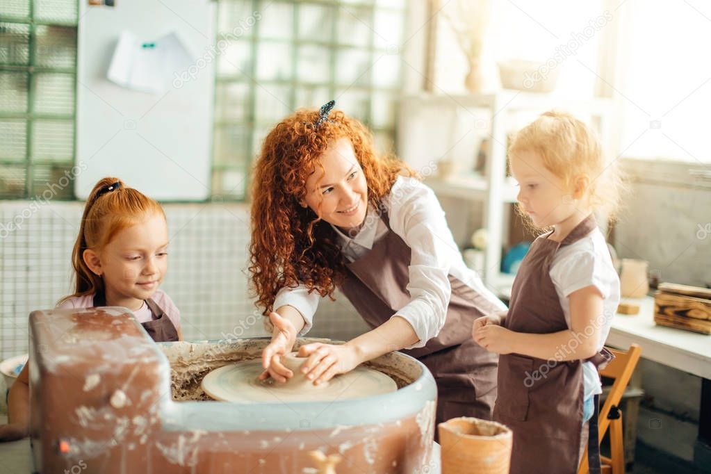 mother and two redhead daughters made clay cup with pottery wheel