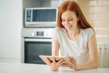 Dijital tablet ile oturan mutlu gülümseyen kadın