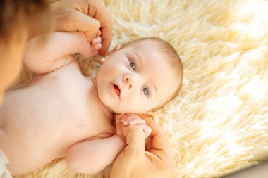 Kameraya bakıyor bebeğim, beyaz battaniye üzerinde yatıyordu