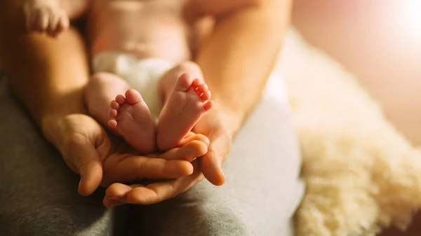 Mamma håller nyfödda babys fötter. Små fötter i kvinnans hand. — Stockfoto