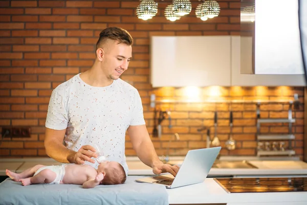 Dad trying to work while standing with his newborn babe in home office interior — Stock Photo, Image