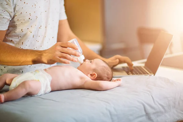 Pappa försöker arbeta stående med sin nyfödda babe i hemmakontor interiör — Stockfoto