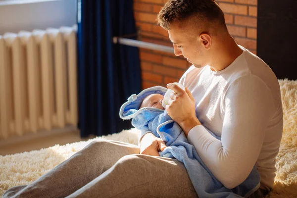 Happy father feeding his newborn son with milk in bed at home — Stock Photo, Image