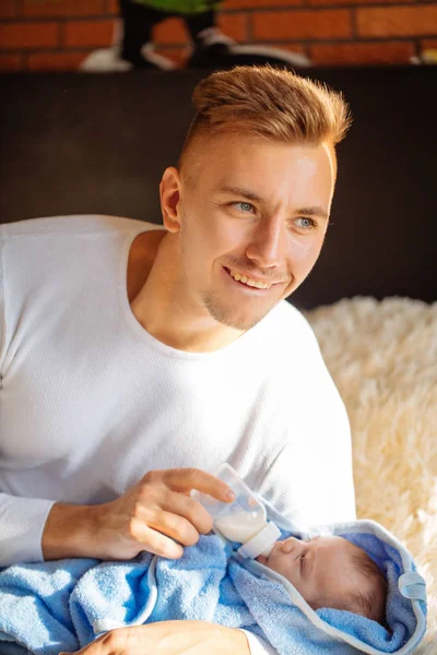 Gelukkig vader zijn pasgeboren zoon vervoederen melk in bed thuis — Stockfoto
