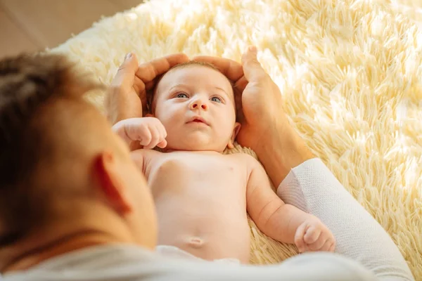 Младенец, глядя в камеру, ложится на белое одеяло — стоковое фото