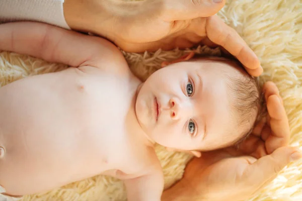 Bebê recém-nascido deitado sorrindo olhando para a câmera enquanto o pai segurando a cabeça — Fotografia de Stock