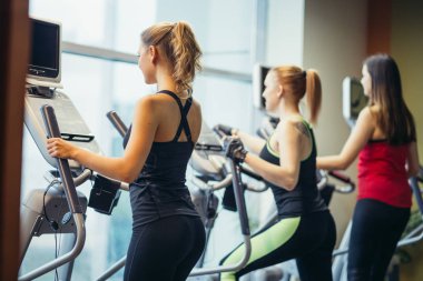 Erkek spor salonunda antrenör makinelerde egzersiz.