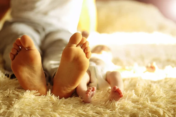 Familia acostada en la cama, sus pies en foco. Madre, padre e hijo recién nacido —  Fotos de Stock