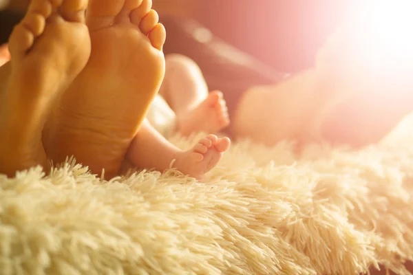 Familia acostada en la cama, sus pies en foco. Madre, padre e hijo recién nacido —  Fotos de Stock