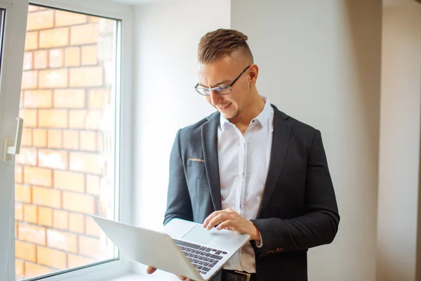 Knappe man met bril, werken met de laptop in office — Stockfoto