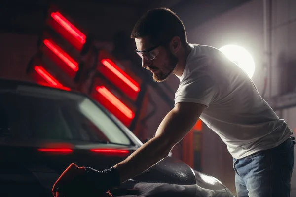 Detaily vozu - muž drží mikrovlákno v ruce a leští auto — Stock fotografie