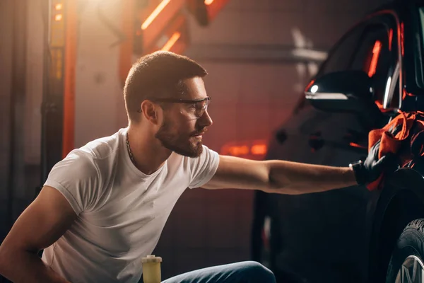 Car detailing - the man holds the microfiber in hand and polishes the car — Stock Photo, Image