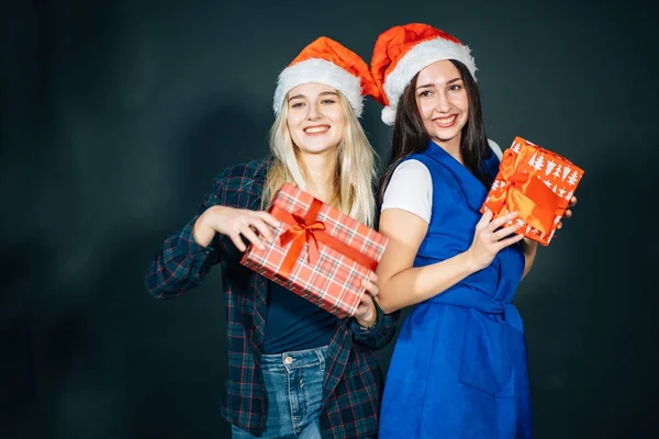 Duas mulheres felizes em chapéus de Santa com caixas de presente de pé — Fotografia de Stock