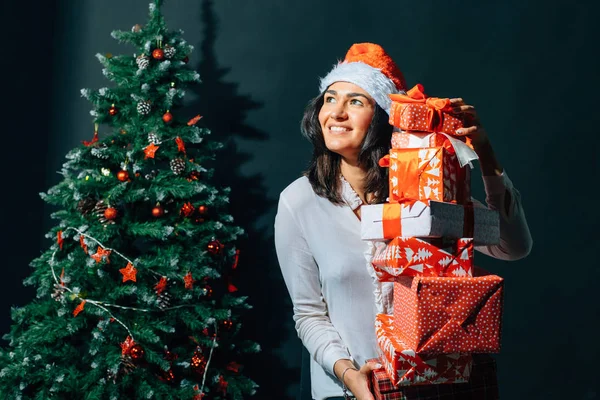 Leende kvinna i santa helper hatt med många presentförpackning — Stockfoto