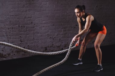 Savaş halatları seansı. Çekici genç fit ve formda sporcu kadın antrenmanı.