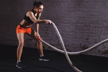 Savaş halatları seansı. Çekici genç fit ve formda sporcu kadın antrenmanı.