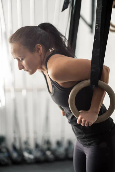 Женщина тренируется с гимнастическими кольцами в тренажерном зале — стоковое фото