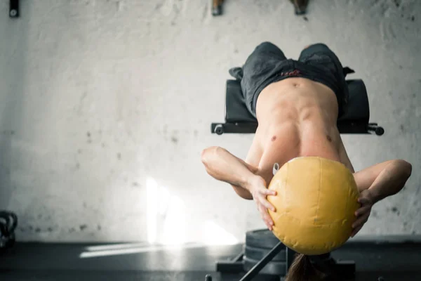 Потужний спортсмен, що виконує абс вправи з медичним м'ячем — стокове фото