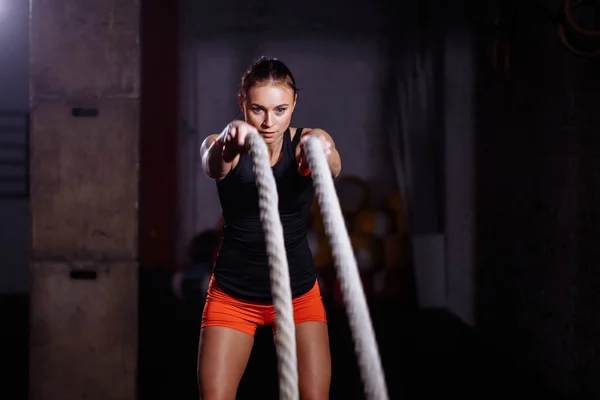 Жінка здійснює вправи з бойовою мотузкою в функціональному тренажерному залі — стокове фото