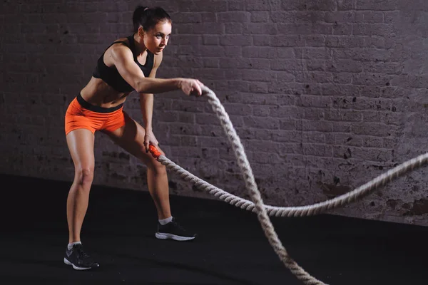 Sesión de cuerdas de batalla. Atractivo entrenamiento de deportista joven en forma y tonificado en el gimnasio — Foto de Stock