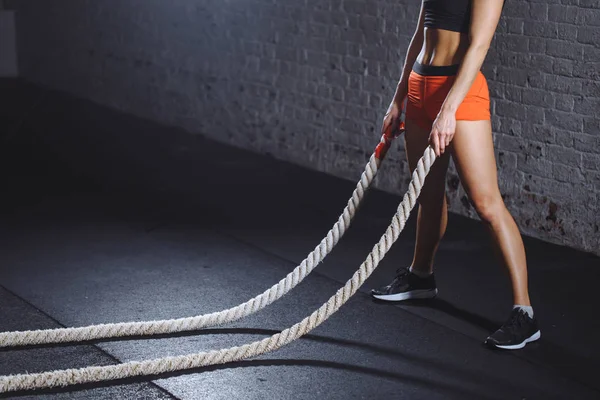 Mujer joven preparándose para hacer ejercicio con cuerdas de batalla en el gimnasio de cross fit — Foto de Stock