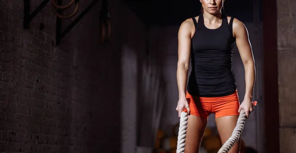 Jonge vrouw voorbereiden om te werken met de slag bij touwen cross fit gym — Stockfoto
