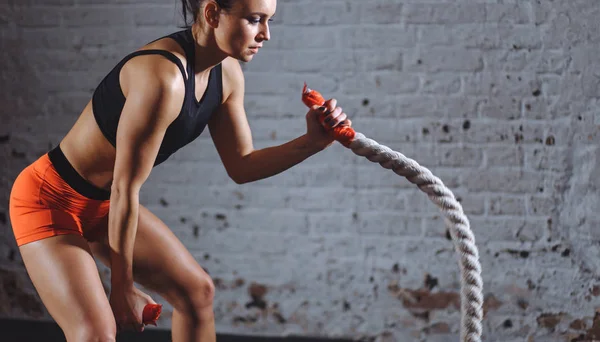 Nahaufnahme Foto einer Frau beim Kampfseiltraining in der Nähe einer weißen Ziegelmauer — Stockfoto