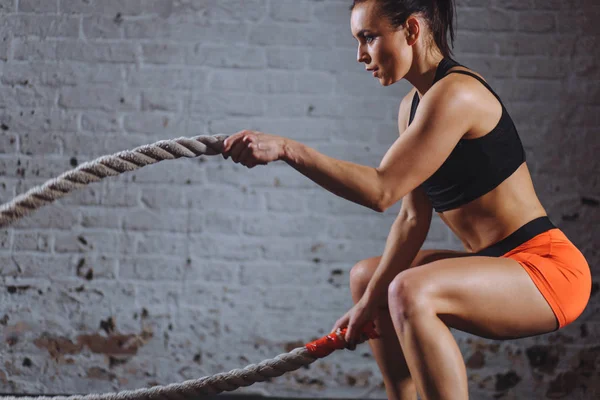 Mujer poderosa hacer ejercicio con cuerdas de batalla en el gimnasio —  Fotos de Stock