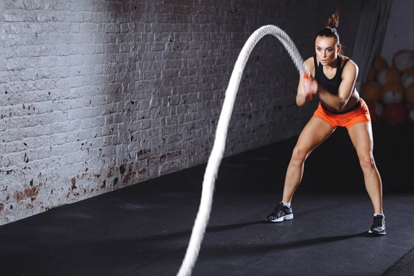 Kobieta robi cross fit ćwiczenia z jednej bitwy liny — Zdjęcie stockowe