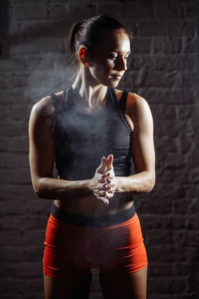 female athlete clapping hands with chalk powder before strength training