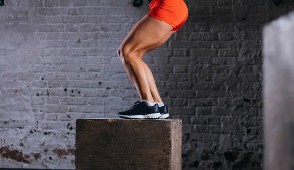 fit woman doing box jump exercise. Muscular woman doing box jumps at gym