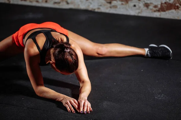 Frauensport Stretching in der Turnhalle mit Ziegelwand und schwarzen Matten — Stockfoto