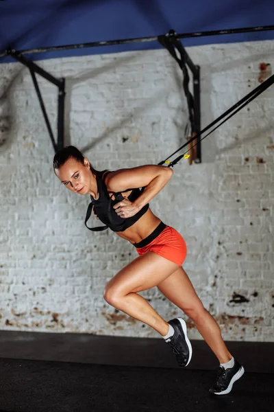 Concepto Trx. señora ejercitando sus músculos con la ayuda del cabestrillo del entrenador de suspensión — Foto de Stock