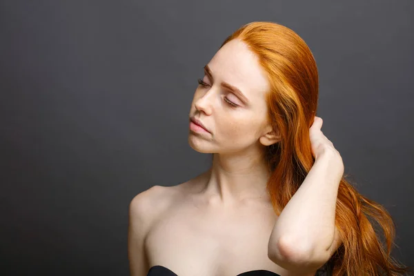 Rossa donna che tiene i capelli sani e lucidi, grigio studio — Foto Stock