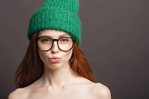 Jengibre mujer usando gafas y verde sombrero puchando sus labios listo para besar — Foto de Stock