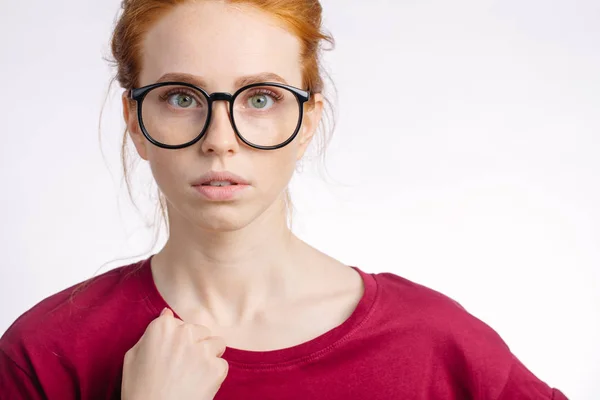 Pelirroja en gafas con nudo de pelo mirando a la cámara sobre fondo blanco —  Fotos de Stock