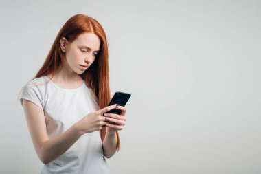 Temiz çilli kızıl saçlı kız akıllı telefon kullanıyor..