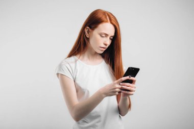 Smartphone ve mesaj atıp tutan gülümseyen bir kızıl saçlı kadın portresi